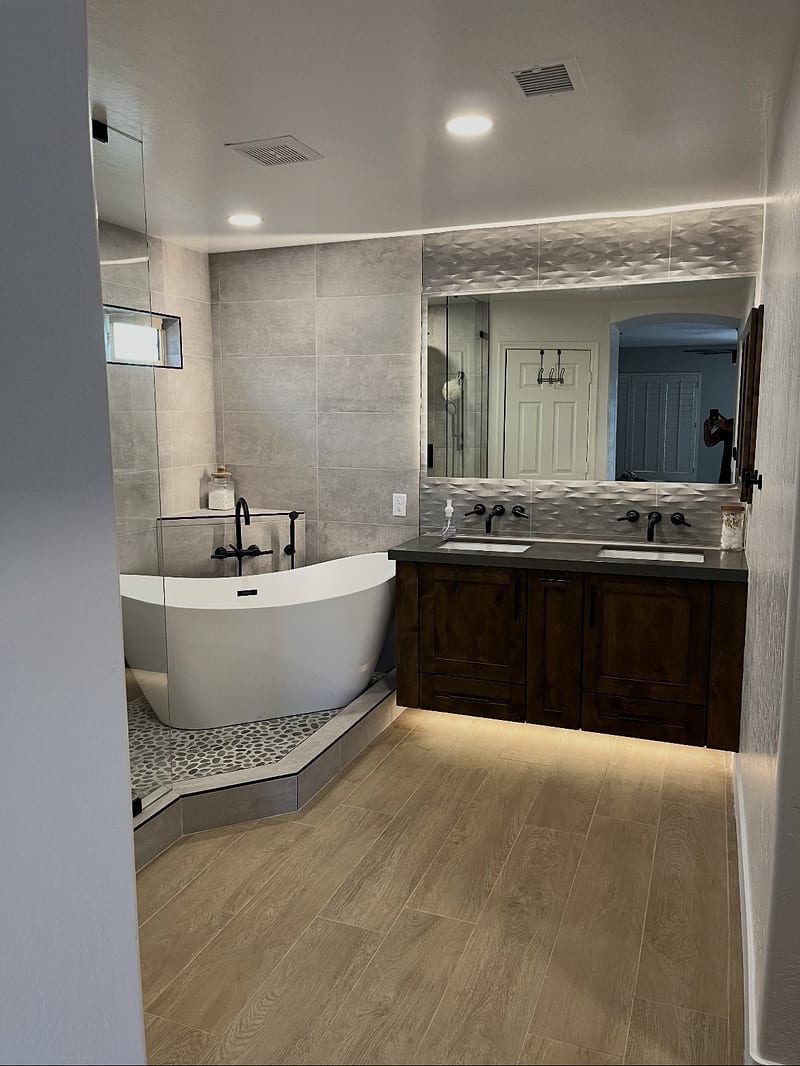 Remodeled bath with freestanding tub and dark wood vanity
