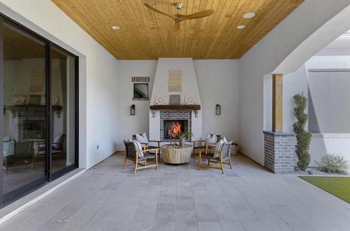 Covered patio with wood ceiling, fireplace, and dining